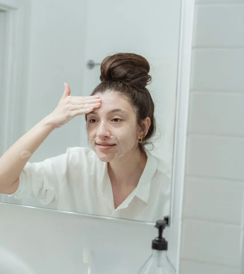 Une femme observe sa peau devant le miroir avant son soin